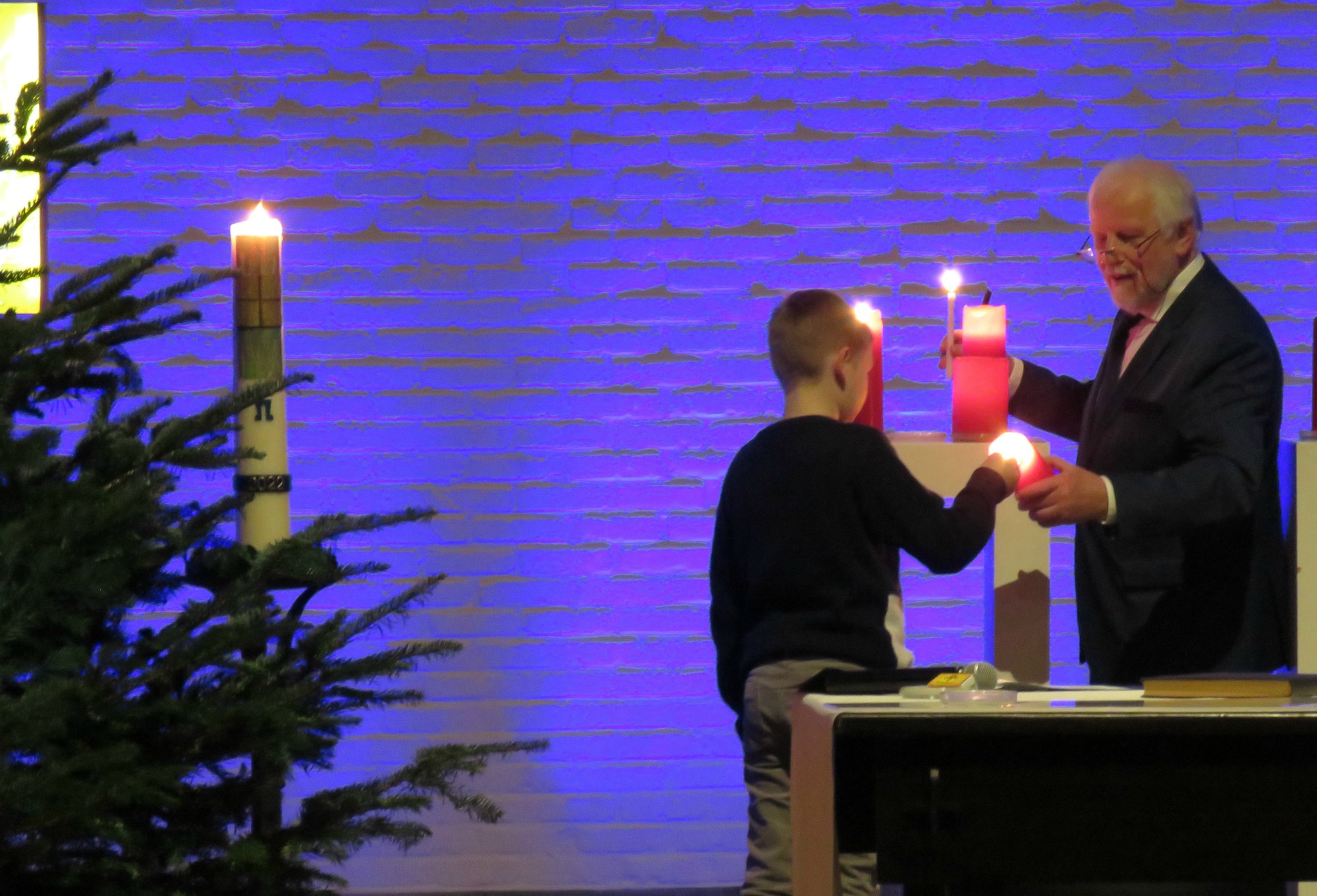 Een vormeling ontsteekt alle rode kaarsen achter het altaar bij de Lichtritus